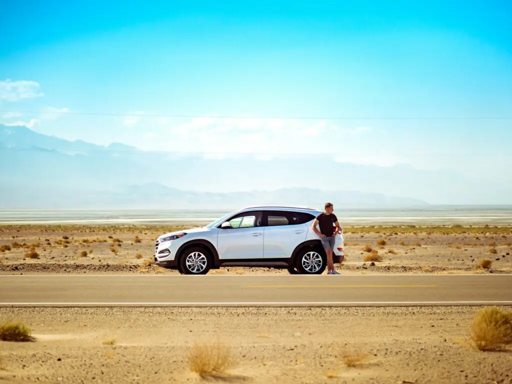 voiture de location blanche dans un paysage désertique avec montagnes en arrière-plan