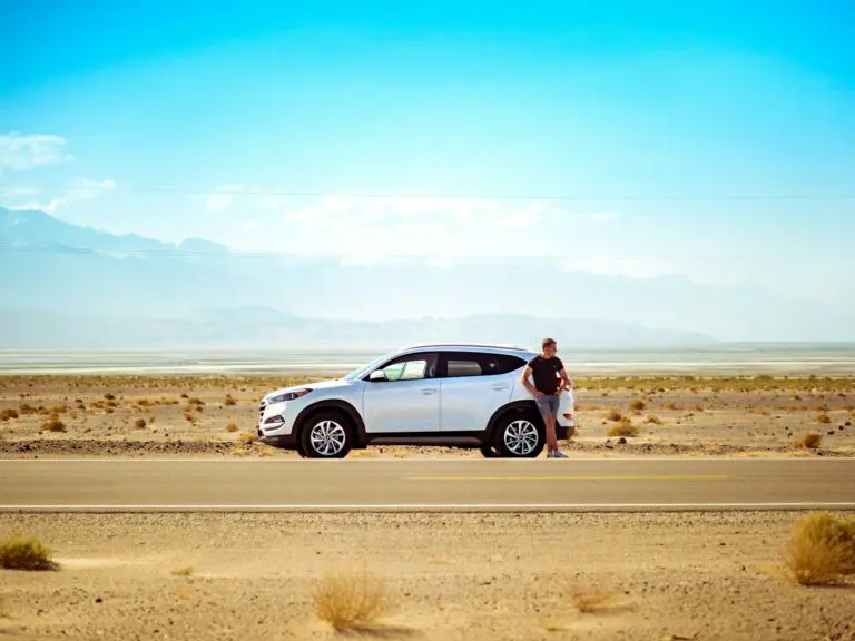 voiture de location blanche dans un paysage désertique avec montagnes en arrière-plan