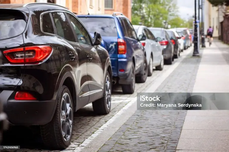 voitures garées en ligne dans une rue urbaine avec trottoir en pavés