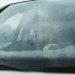 conducteur derrière un pare-brise embuée et mouillé