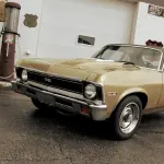 chevrolet nova ss beige des années 1970 garée devant un garage rétro