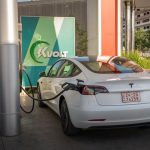 A white Tesla Model 3 charging at an outdoor electric vehicle station with Kvolt branding.