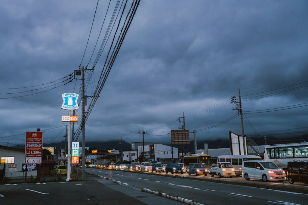 Cars lined up on a street under stormy skies.