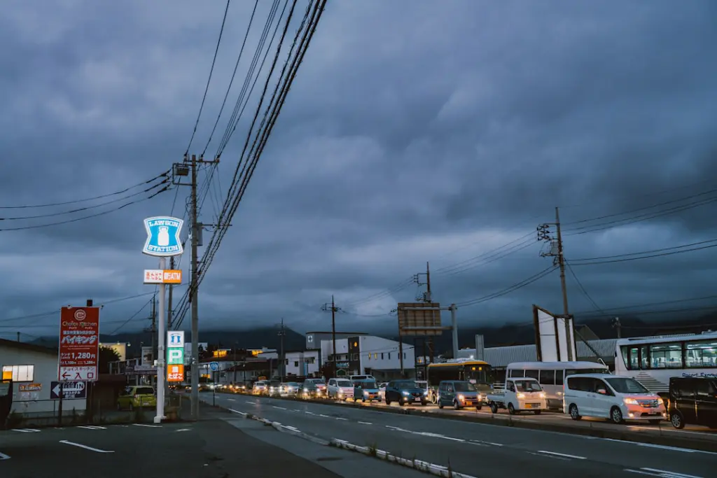 Cars lined up on a street under stormy skies.