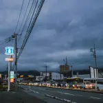 Cars lined up on a street under stormy skies.