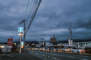 Cars lined up on a street under stormy skies.