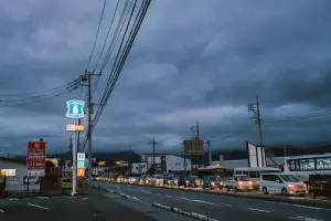 Cars lined up on a street under stormy skies.