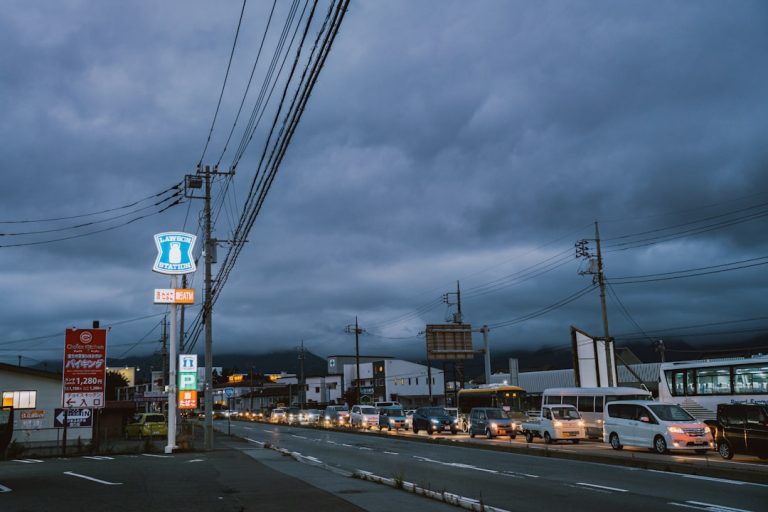 Cars lined up on a street under stormy skies.