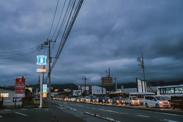 Cars lined up on a street under stormy skies.