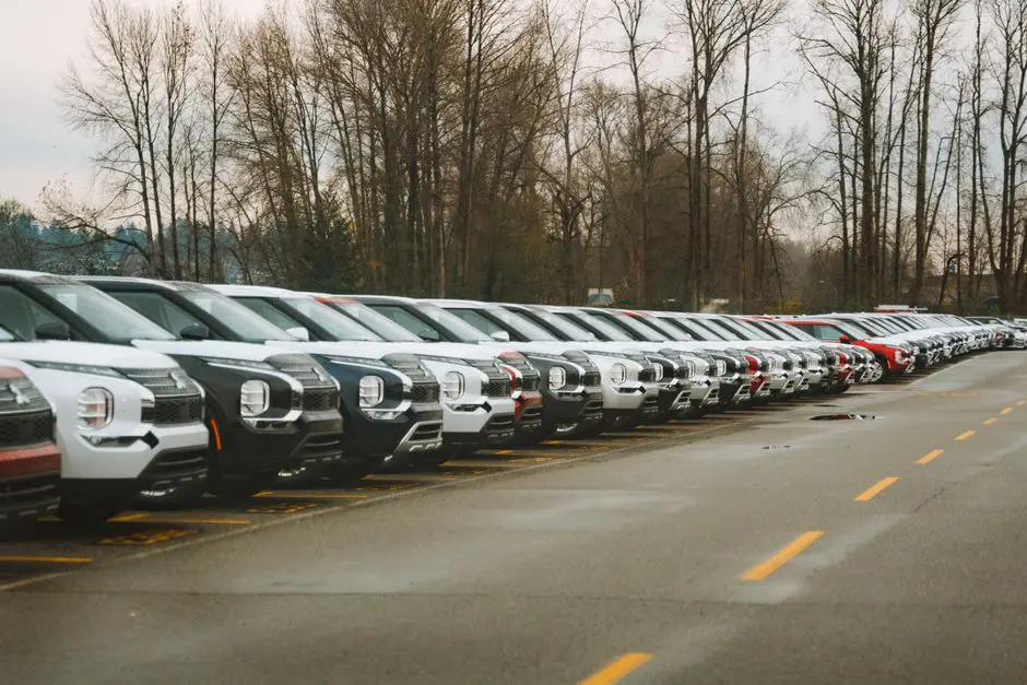 A line of brand new SUVs in an outdoor parking lot during a cloudy day.