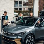 A group of people standing around a silver car
